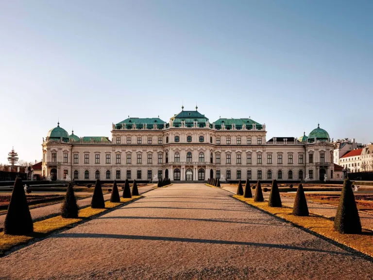 The Upper Belvedere palace in Vienna seen along the gravel avenue of its formal gardens, lined with clipped conical yews.
