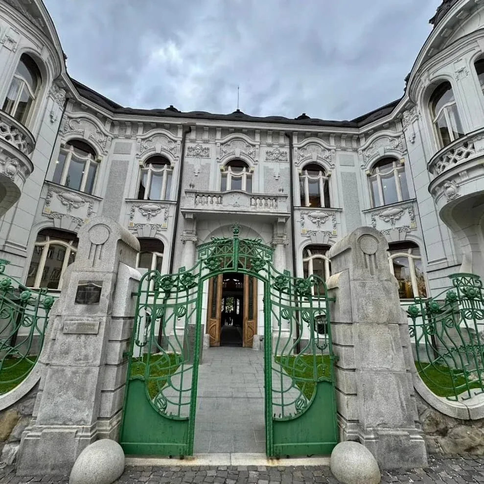 Rosenfeld Palace in Žilina, an Art Nouveau mansion built as a quarter-scale copy of the Belvedere in Vienna, seen through its green wrought-iron gates.