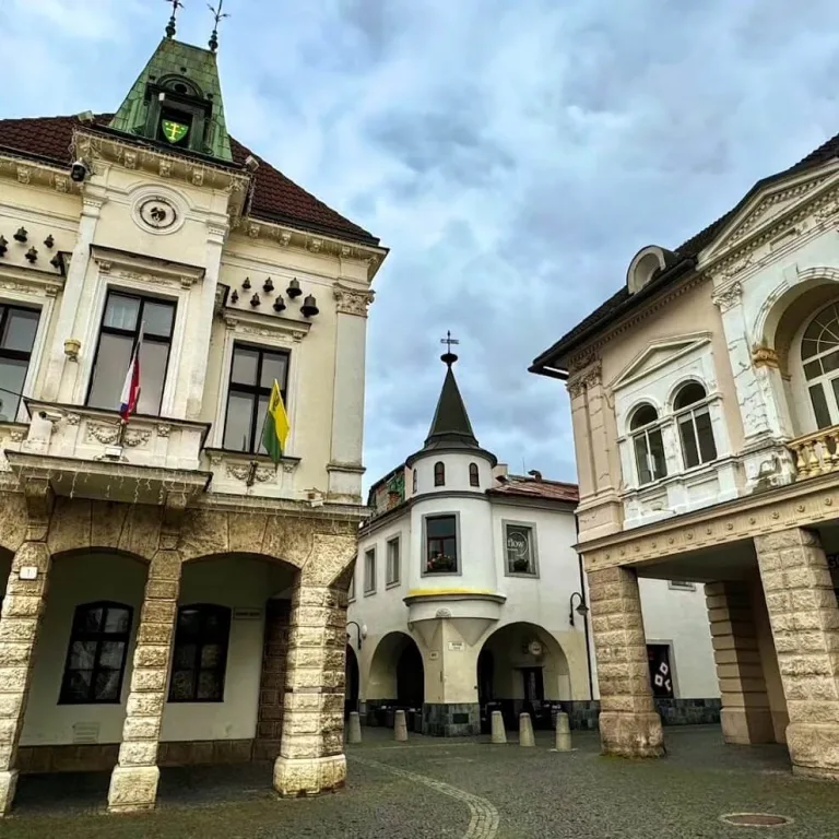 The arcaded houses and town hall of Mariánske Square in Žilina under a cloudy sky.