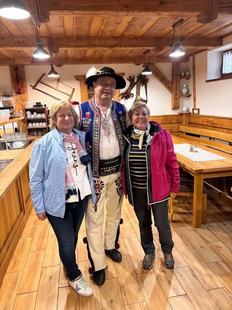 Two guests with their host in full Slovak folk costume at a folk dinner in Stará Lesná.