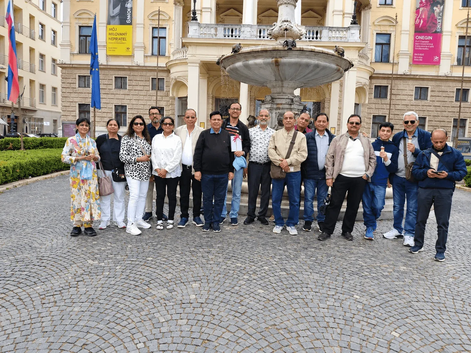 Un groupe de voyageurs photographié devant la fontaine située face au bâtiment historique du Théâtre national slovaque à Bratislava.