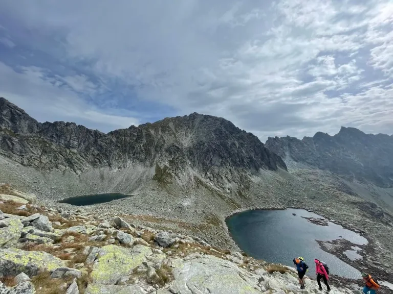Two glacial tarns in a rocky high valley of the Tatras, walkers climbing the slabs in the foreground.
