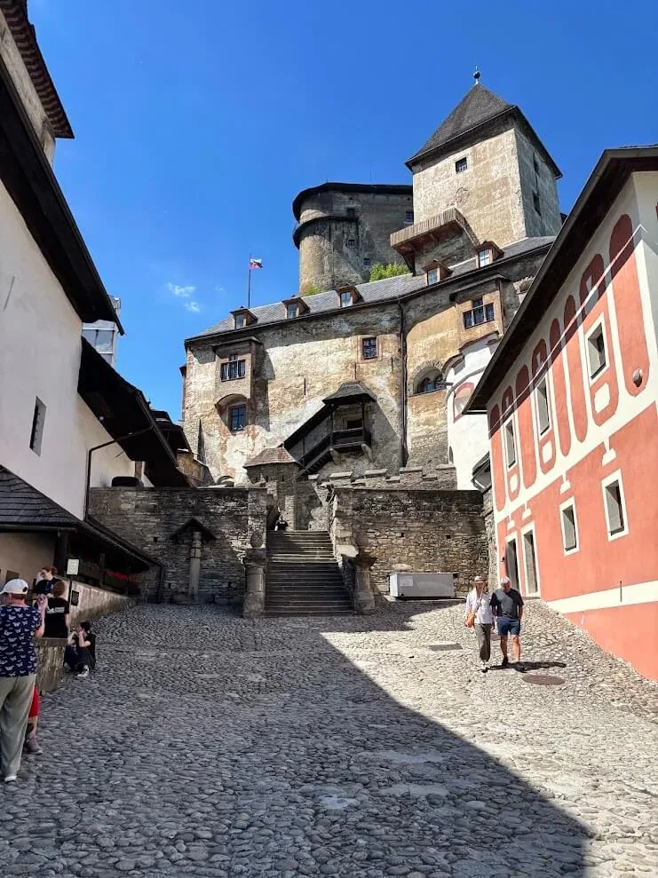 The cobbled approach inside Orava Castle, its stone walls, timber galleries and tower rising above the steps.