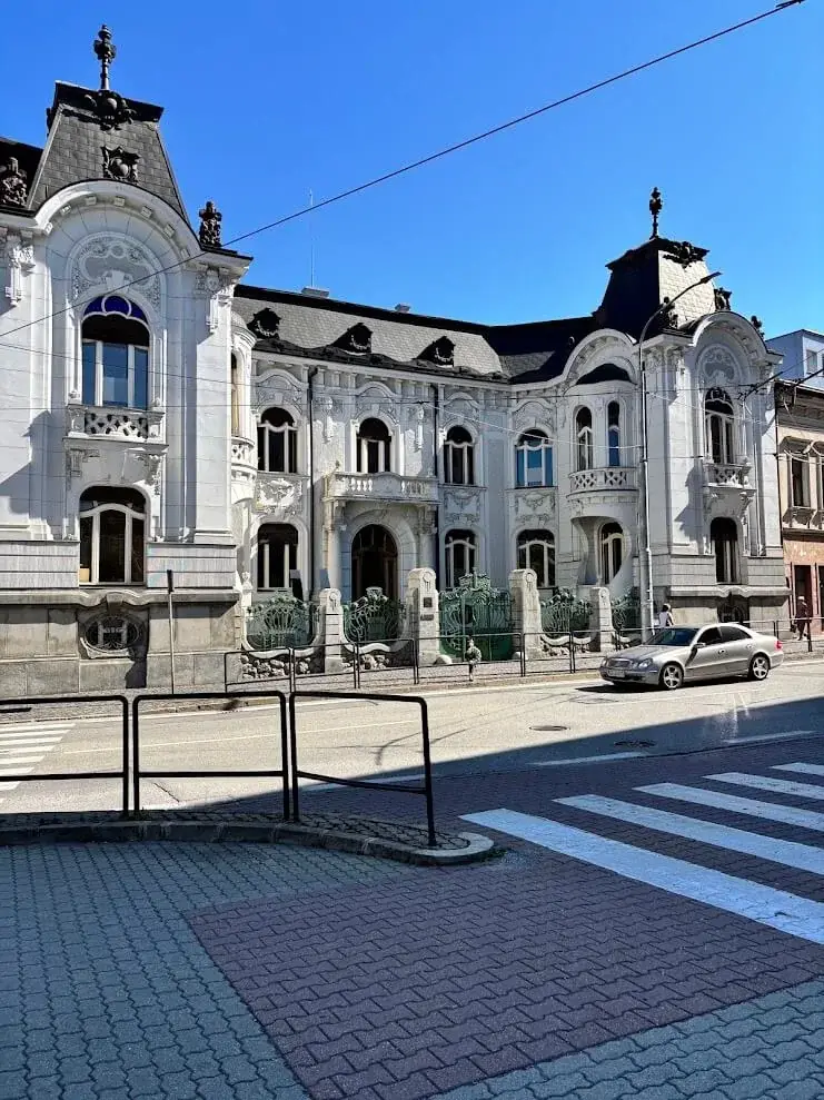 The Rosenfeld Palace in Žilina seen from the street, its white ornamented art-nouveau façade, ornate gables and green ironwork.