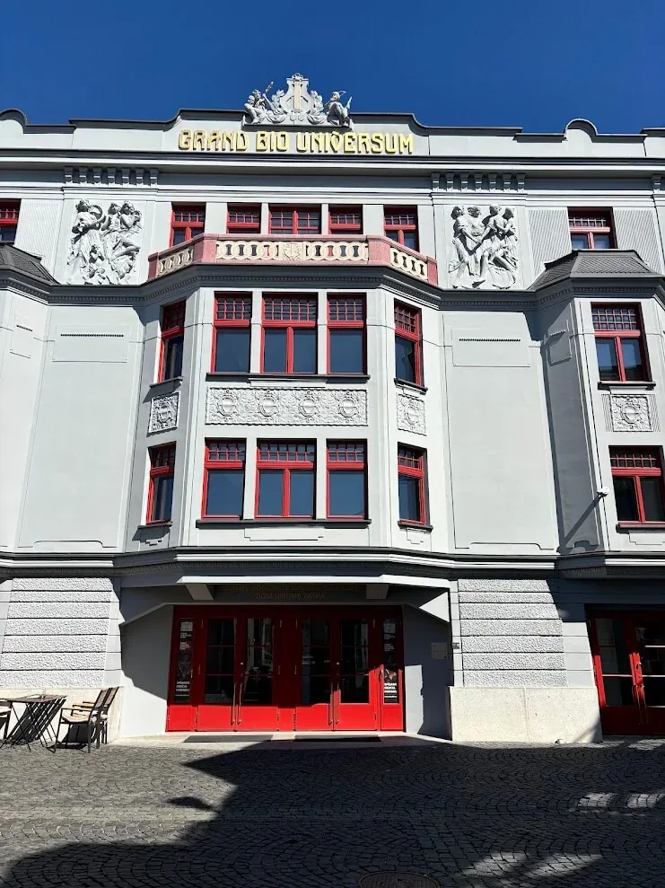The restored façade of the Grand Bio Universum cinema in Žilina, its stone reliefs and bright red window frames.