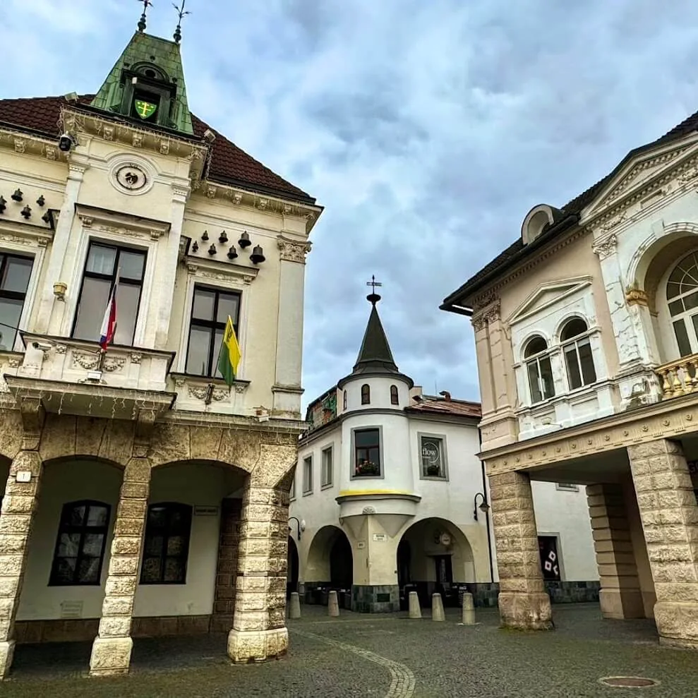 Mariánske námestie in Žilina, its arcaded burgher houses and a corner turret under a grey sky.