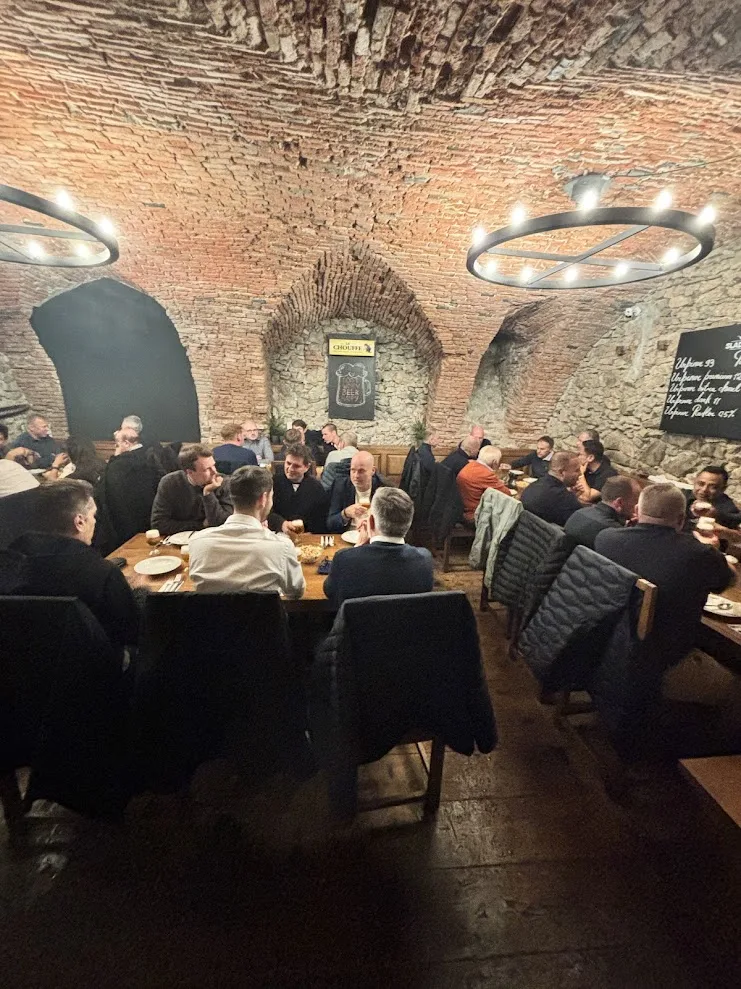 A group dinner under the brick vaults of the Sladovna Beer House in Bratislava, delegates seated along long wooden tables.