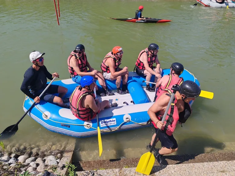 A raft crew pulling in to the bank at the Čunovo white-water centre south of Bratislava, a kayaker out on the course behind them.