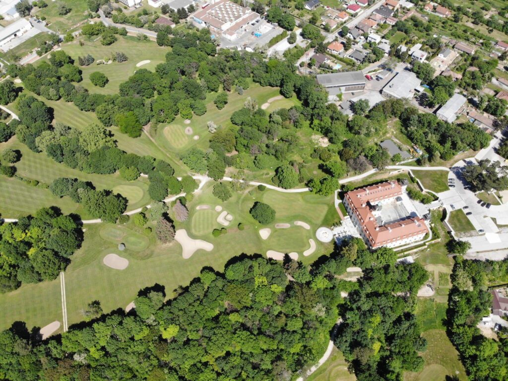 Aerial view of a lush golf course in Bernolákovo, Slovakia, featuring sand bunkers, fairways, and a historic chateau. Ideal for a golf incentive in Slovakia