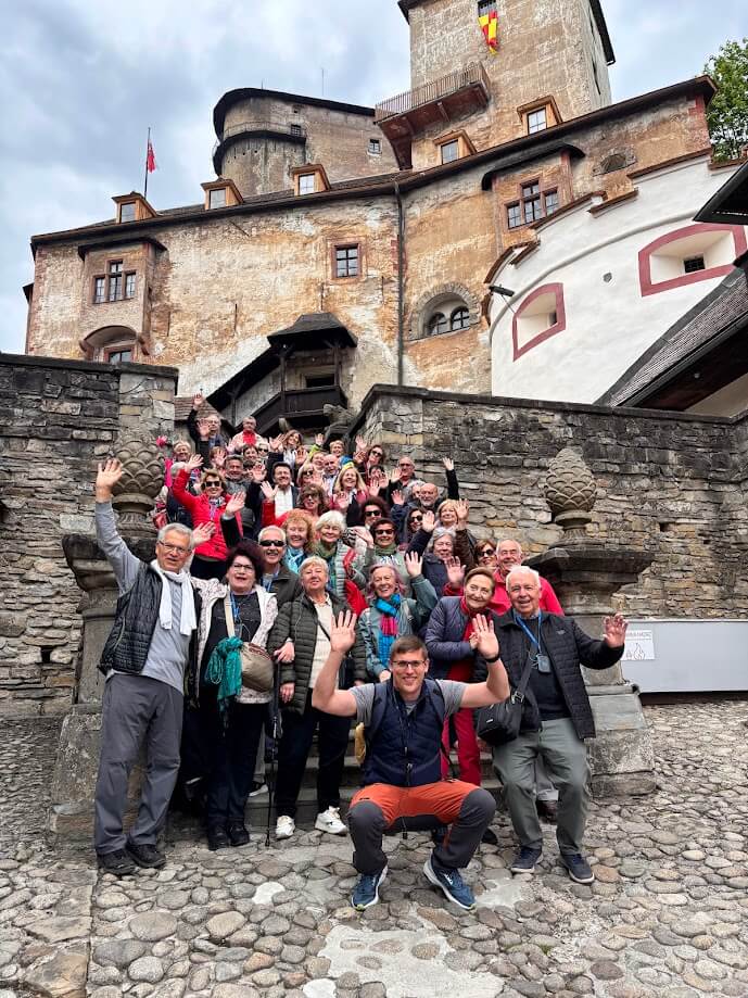 Grupo de turistas posando felices en las escaleras del Castillo de Orava durante un circuito grupal por Eslovaquia con guía local